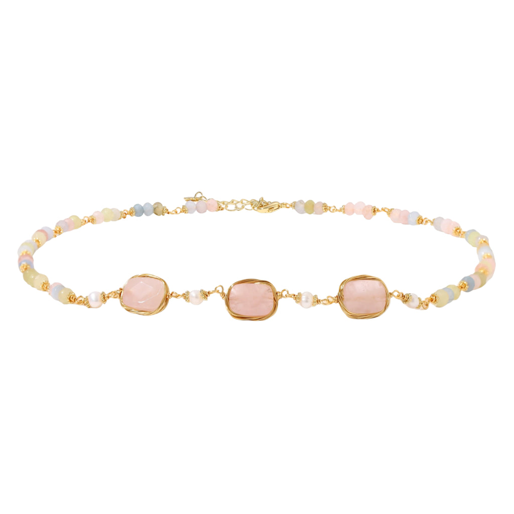 Gold necklace with three rose quartz stones, multicolor pastel beads, and pearl accents on white background.