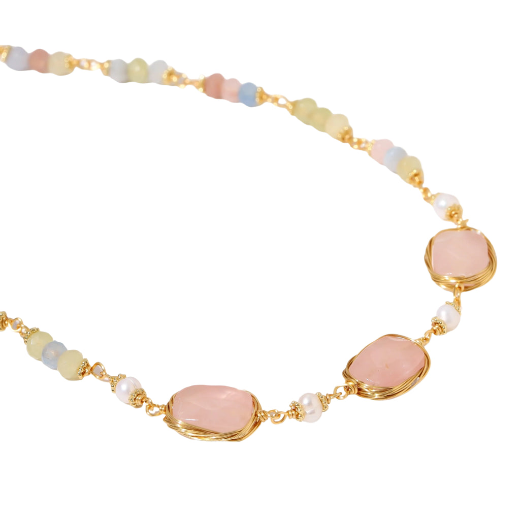 Gold necklace with three rose quartz stones, multicolor pastel beads, and pearl accents on white background.