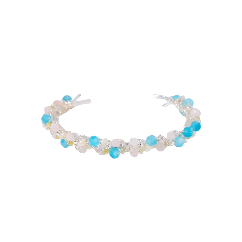 Delicate wire-wrapped bracelet featuring turquoise, rose quartz, freshwater pearls, and zircon on a white background.